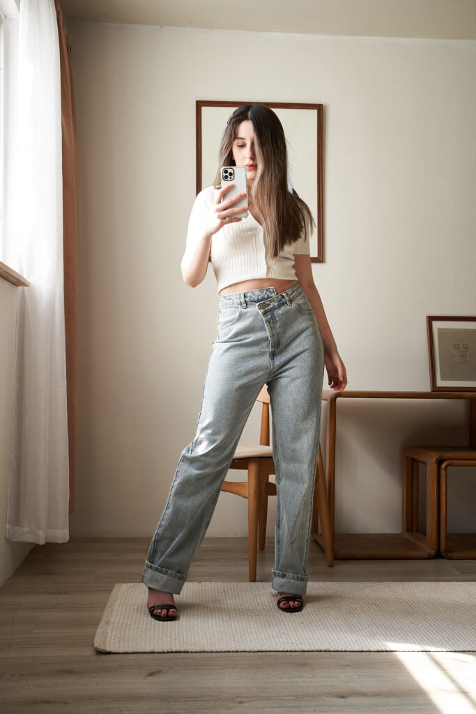 Gabriela Inzunza for Avice a stylish room with a wooden chair a table and a framed artwork with the model taking a mirror selfie.